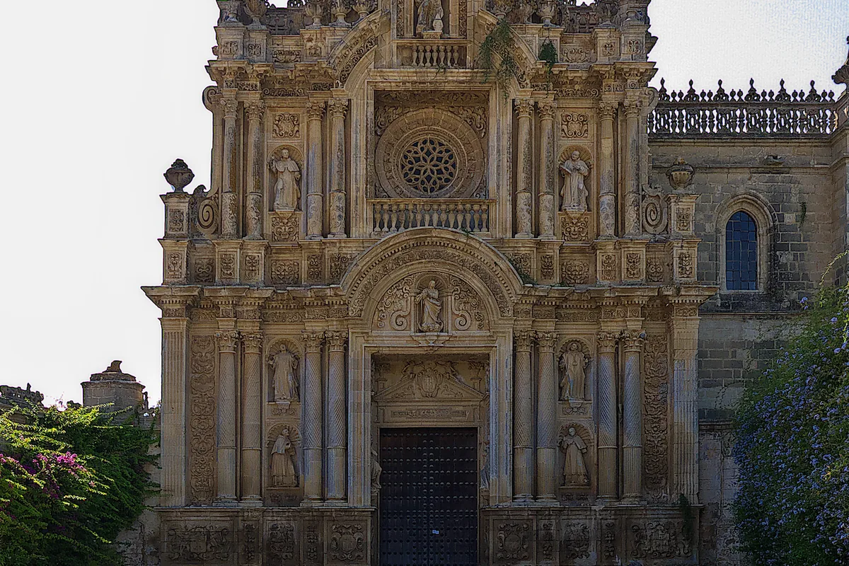 The carved stone gateway of the Charterhouse of Jerez, with columns, statues in niches and a rounded pediment